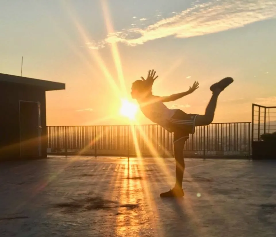 Jes practicing Qi Gong on a rooftop at sunrise